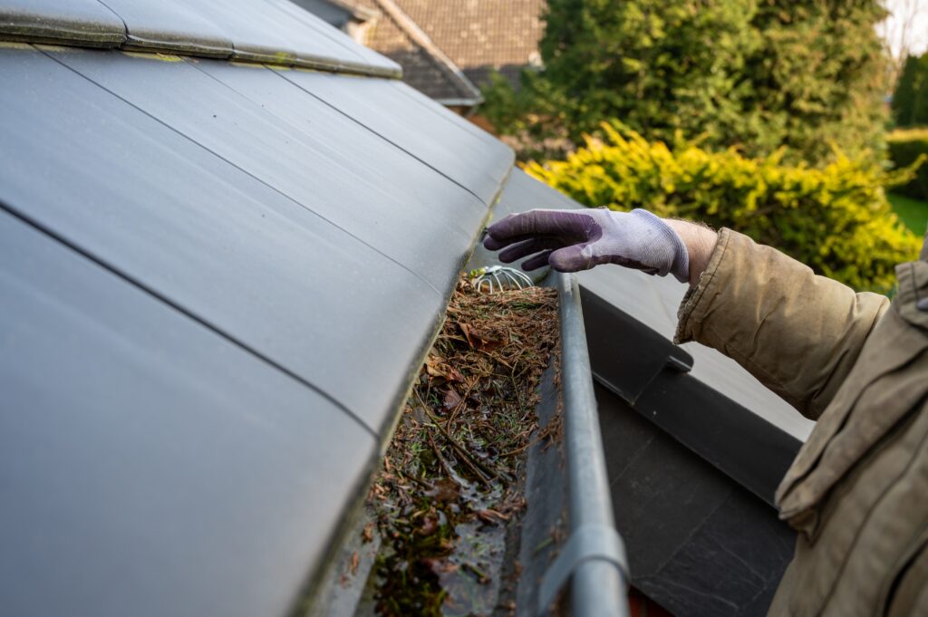 man cleaning blocked rain gutter