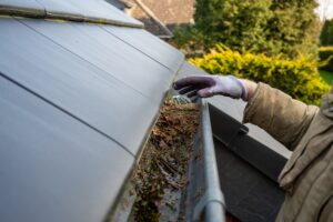 man cleaning blocked rain gutter