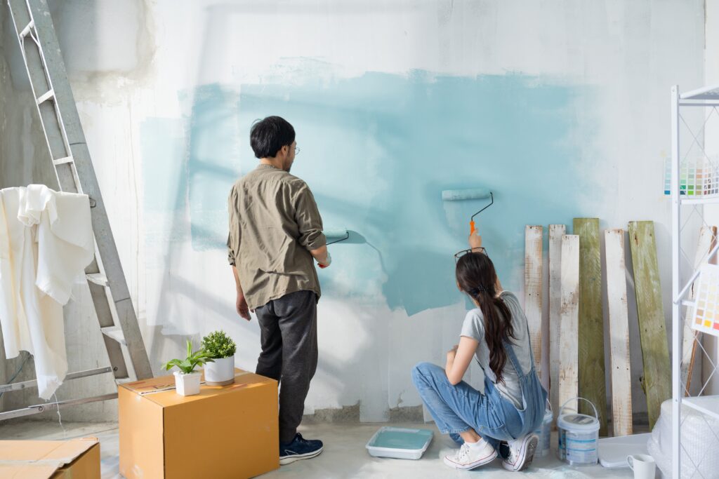 young asian couple repairing and painting the wall