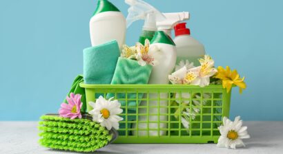 basket with set of cleaning supplies and flowers