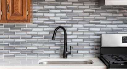 a kitchen faucet detail with a grey tile backsplash