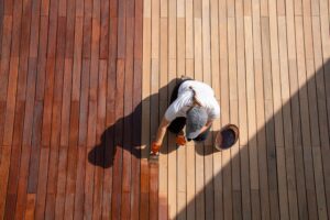 overhead view of workman staining wood outside