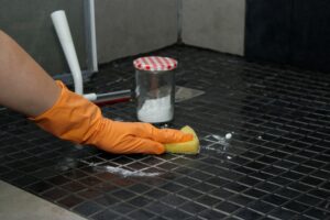 close up of womans hands in orange gloves cleaning shower