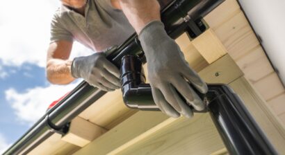 worker installing gutter system on roof