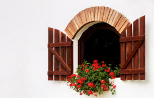 arched window with open shutters and flower pots