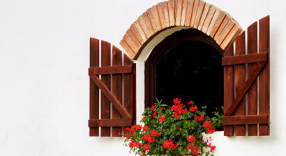 arched window with open shutters and flower pots