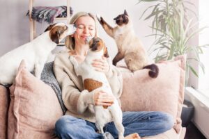 happy woman playing with her dogs and cats on the couch