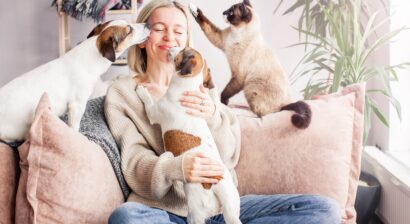 happy woman playing with her dogs and cats on the couch