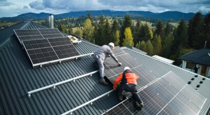 electricians building solar panels onto roof of house
