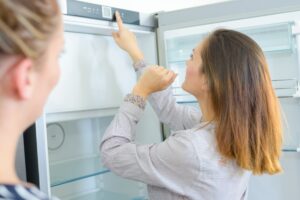 woman checking refrigerator temperature