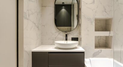 the interior of a small modern bathroom with a sink directly next to the shower