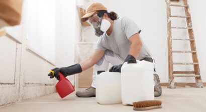 in home renovation with man cleaning black mold with gloves, spray bottle and mask on