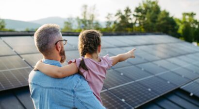 dad carrying little girl pointing at solar on roof