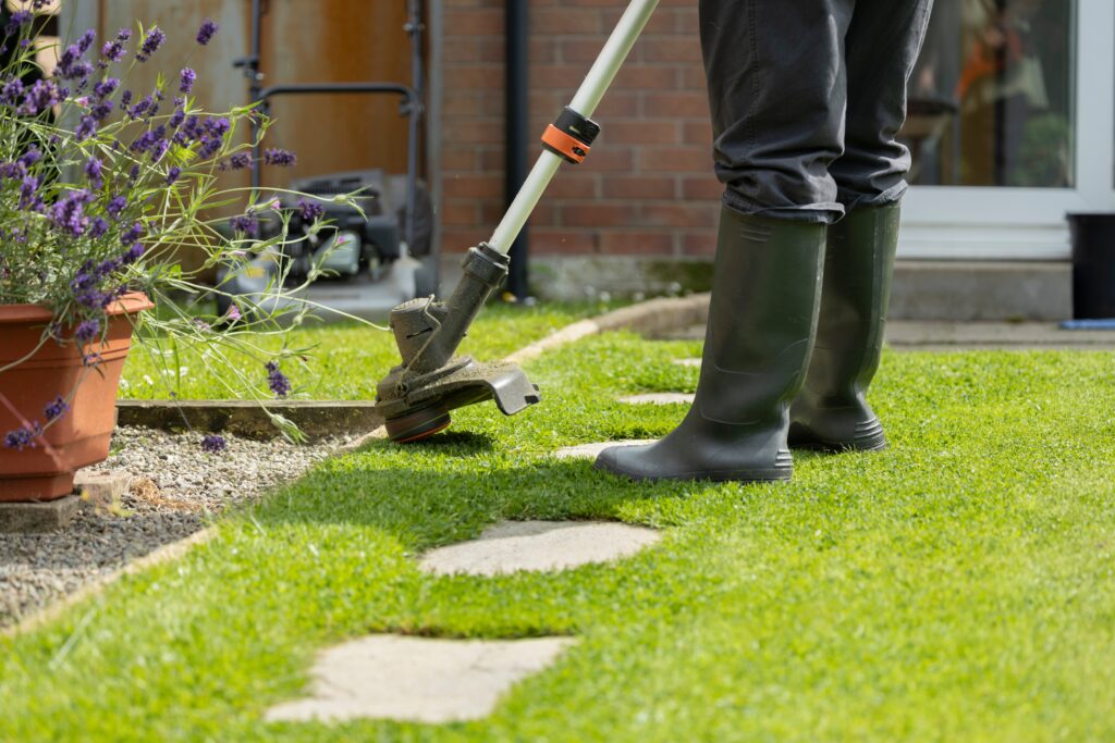 woman in pants and black boots using an edger