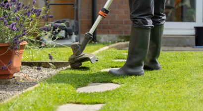 woman in pants and black boots using an edger