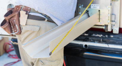 worker measuring an aluminum rain gutter