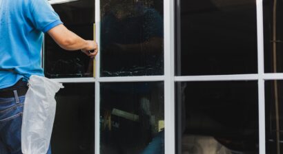 worker using scraper before installing window tinting film