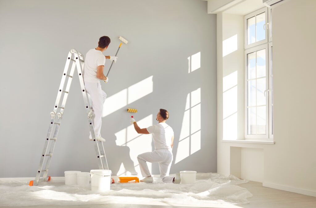 two male workers painting the interior of a home