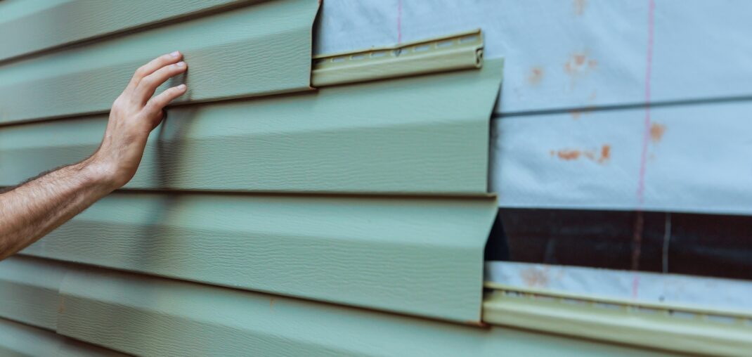 contractor installing vinyl siding on home