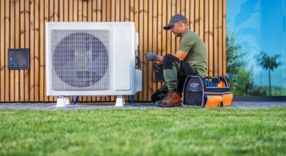 technician servicing an air condition unit located beside a home