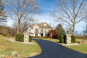 asphalt driveway leading up to large country house
