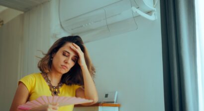 woman using a hand fan with a broken air conditioner