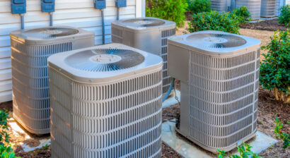 horizontal shot of four air conditioners outside home