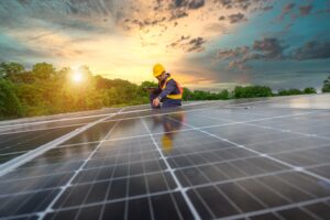 a worker installing solar panels with a sunset