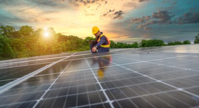 a worker installing solar panels with a sunset