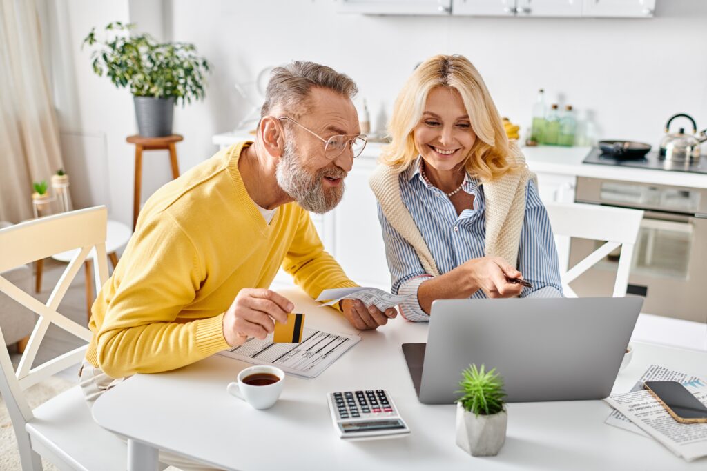 a couple sitting at a table on a laptop with a credit card