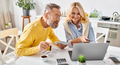 a couple sitting at a table on a laptop with a credit card