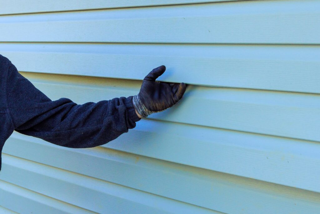 siding professionals hand holding siding with a glove on