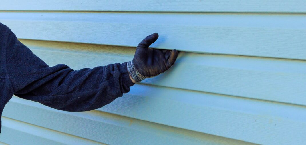 siding professionals hand holding siding with a glove on