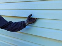 siding professionals hand holding siding with a glove on
