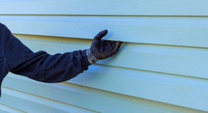 siding professionals hand holding siding with a glove on