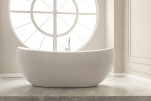 white modern bathroom with white bathtub and round window