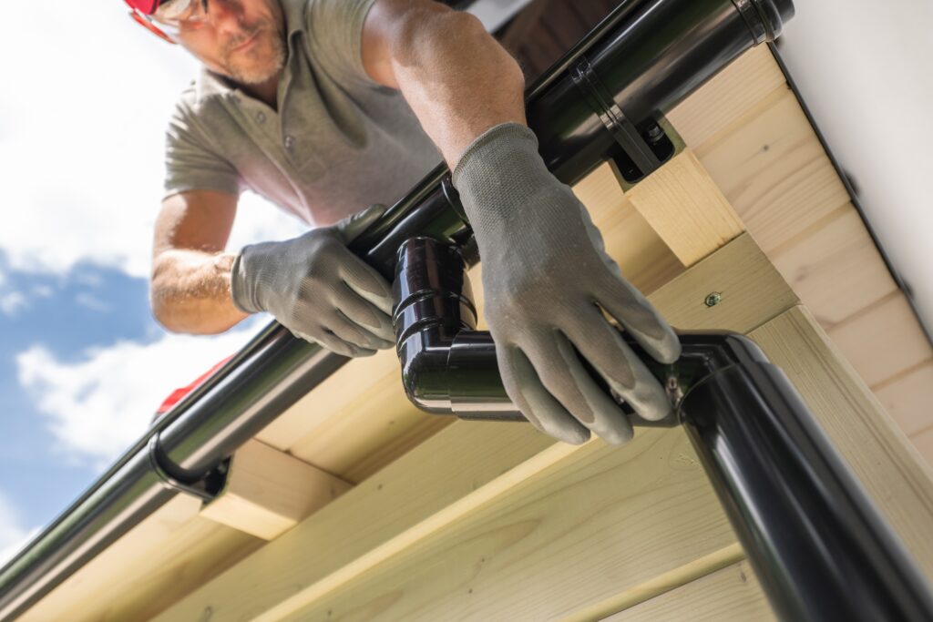 worker installing gutter system on roof
