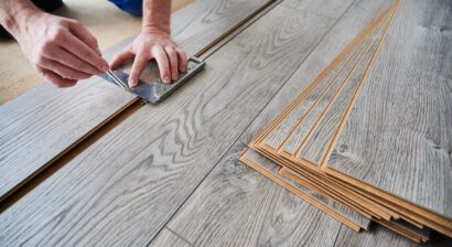 close up of male worker using ruler for flooring installation