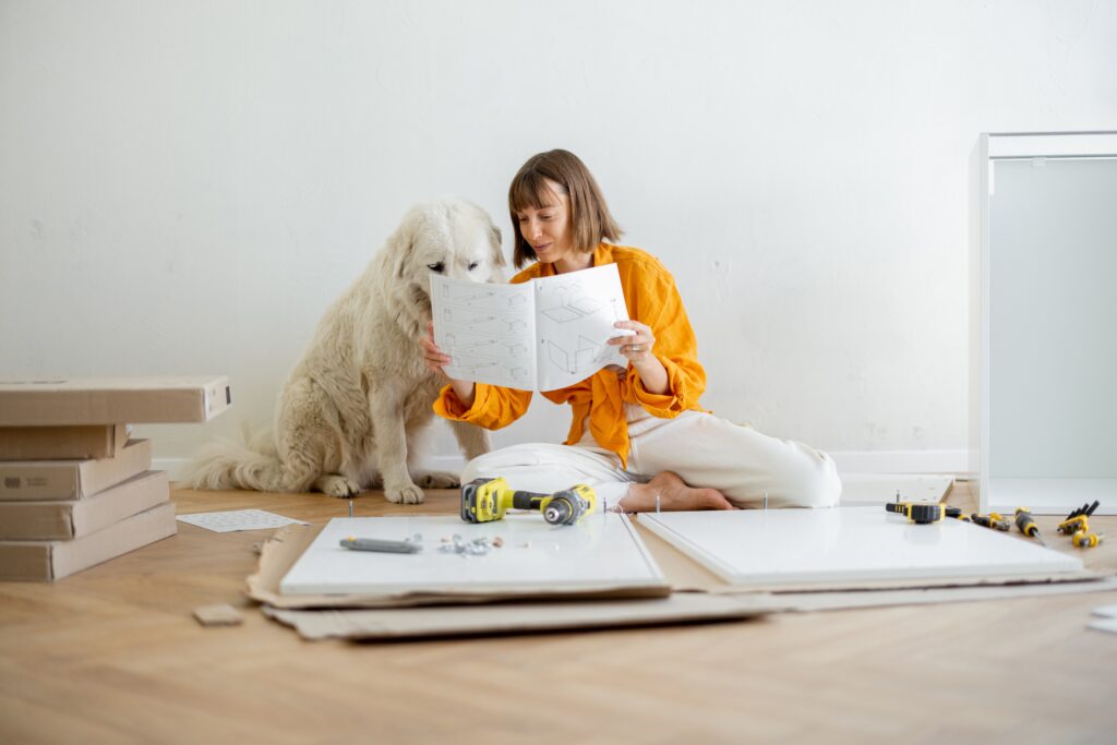 woman assembles furniture while sitting with dog