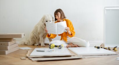 woman assembles furniture while sitting with dog