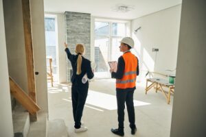 woman and contractor standing in room that is being remodeled