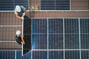 two male technicians installing solar panels on a roof