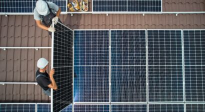 two male technicians installing solar panels on a roof