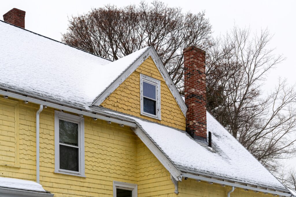 snow covered roof of a yellow house