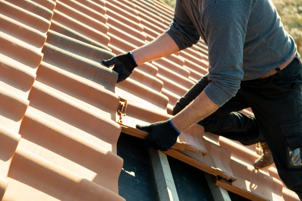 closeup of worker replacing tiles on a roof