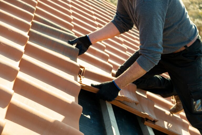 closeup of worker replacing tiles on a roof