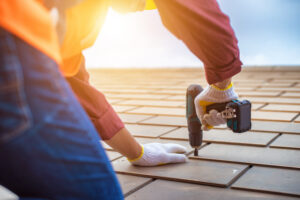 gray roof repair with a contractor drilling